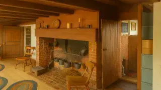 Brightened interior of 1722 Nantucket home with fireplace and wood beams.