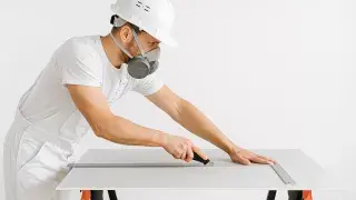 Construction worker installing drywall sheet.