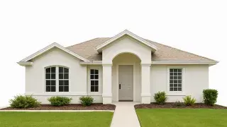 Single-story small white house with gable roof, clean facade, and minimal landscaping.