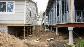 Raised houses supported by helical piles and piers on an active construction site.