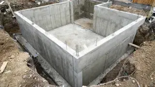 Basement foundation under construction with poured concrete walls and open excavation.