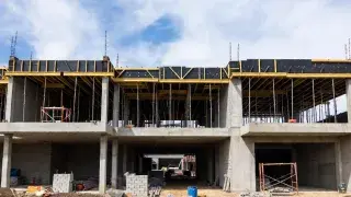 Partial concrete building structure under construction with scaffolding and construction materials, representing a CMAR project site.