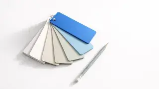 Paint swatch fan with one cobalt blue card beside a pencil on a white surface.
