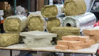 Mixed insulation materials on a workshop table, including batts, rigid foam, and foil-faced rolls.