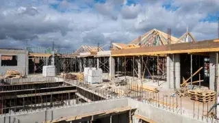 Concrete, masonry, and roof framing in progress on an active building site.
