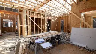 Residential construction site showing wooden framing, foundation, and structural layout.