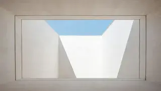 Framed architectural void formed by white concrete walls and layered openings to the sky.