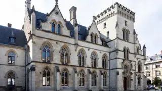 Gothic civic building with pointed arch windows, tower, and stone facade.