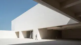 Architectural space with a small human figure under a deep overhang showing scale and proportion.