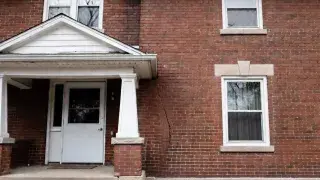 Brick house exterior with a diagonal settlement crack running toward the foundation.