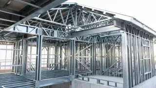 Cold-formed steel house frame with steel roof trusses over the main volume.