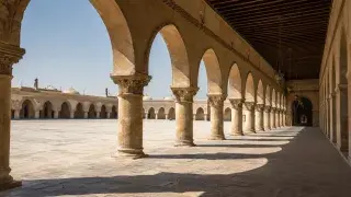 Islamic arcade with repeated stone arches casting shade across a courtyard walkway.