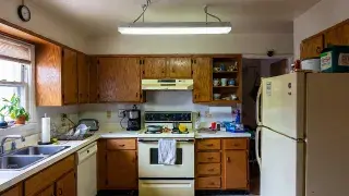 Dated 1980s kitchen with oak cabinets, almond appliances, fluorescent light, and laminate counters.