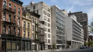 City street showing older masonry buildings beside cleaner early modern buildings with glass, steel, and concrete facades.