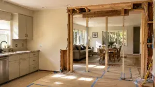 Kitchen wall removal opening with exposed framing and temporary support.