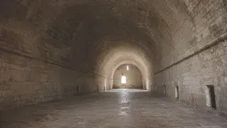 Long stone hall covered by a continuous barrel vault above thick masonry side walls.