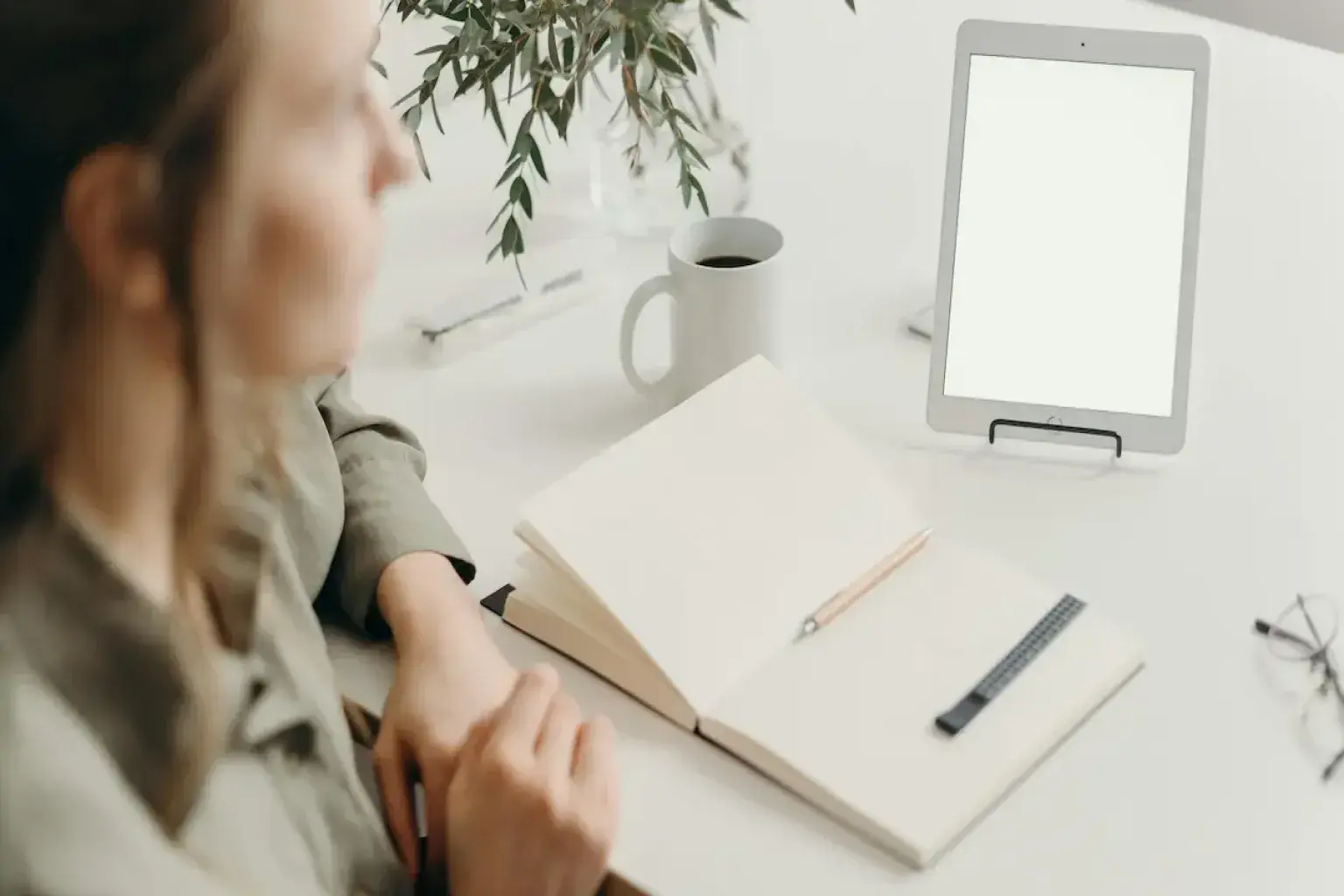 interior designer sitting beside a table with an iPad, paper, and pen, looking distant and confused as if struggling with too many ideas