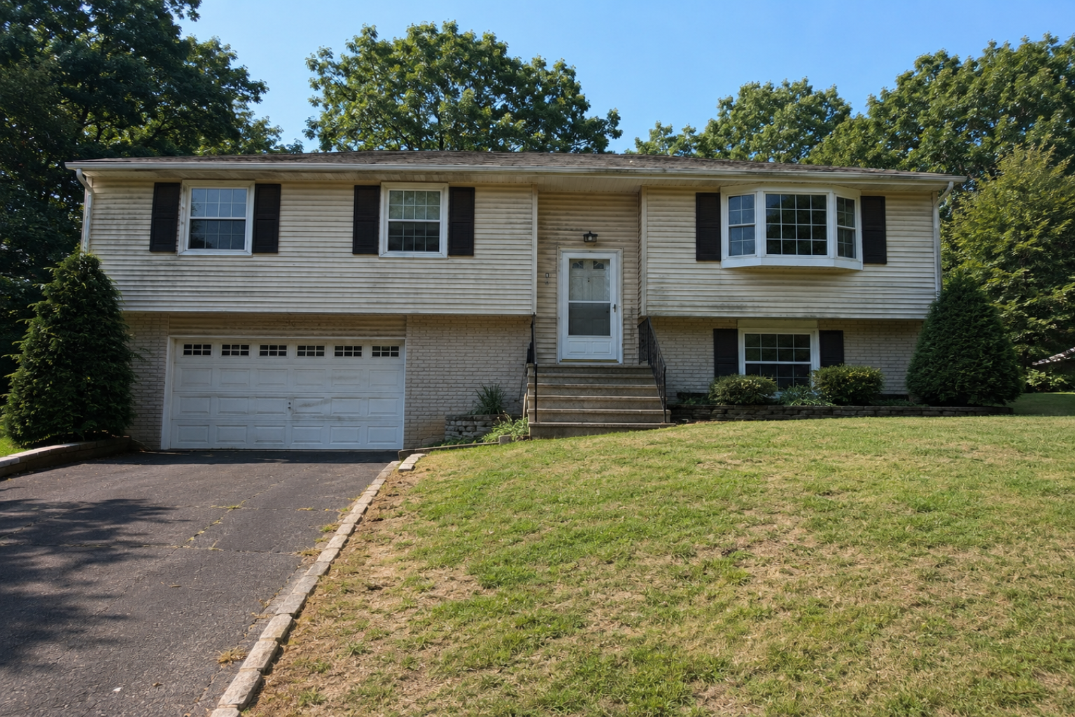 Dated raised ranch exterior with worn lawn, plain stairs, and weak front entry before remodeling.