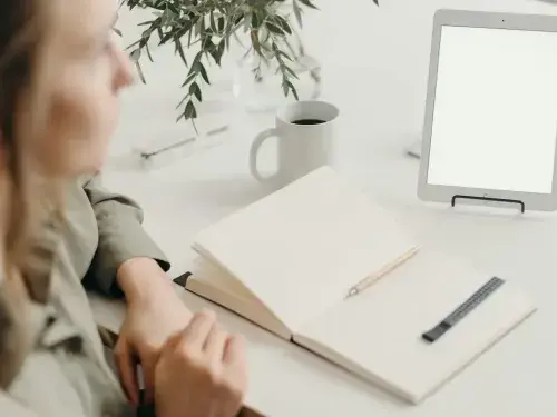 interior designer sitting beside a table with an iPad, paper, and pen, looking distant and confused as if struggling with too many ideas