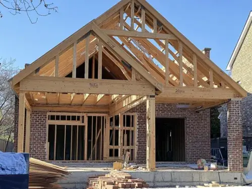 A residential house under construction with a partially completed wooden frame using prefabricated timber trusses.