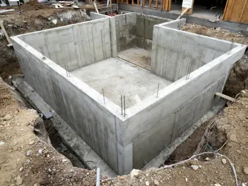 Basement foundation under construction with poured concrete walls and open excavation.