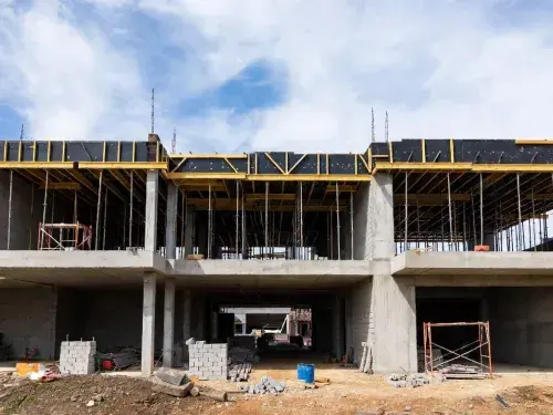 Partial concrete building structure under construction with scaffolding and construction materials, representing a CMAR project site.