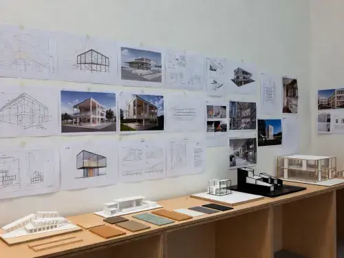 Architecture studio wall with sustainable design course boards, models, and material samples.