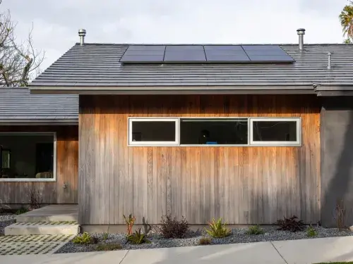 Renovated older house facade with upgraded windows, durable cladding, and clean energy-conscious detailing.
