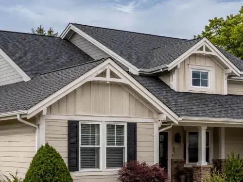 House with multiple gable roof lines showing front gables, ridge lines, sloped roof planes, eaves, gutters, and asphalt shingles.