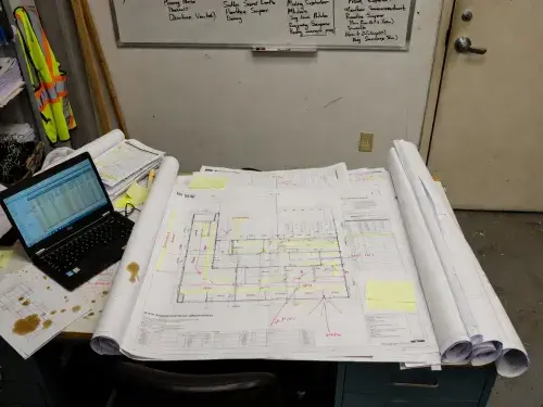 Pre-construction planning documents, schedules, and marked-up drawings in a site office