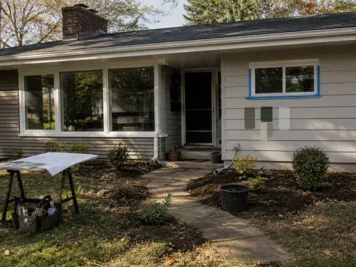 Small ranch house being updated with paint samples, large front windows, landscaping work, and renovation plans.