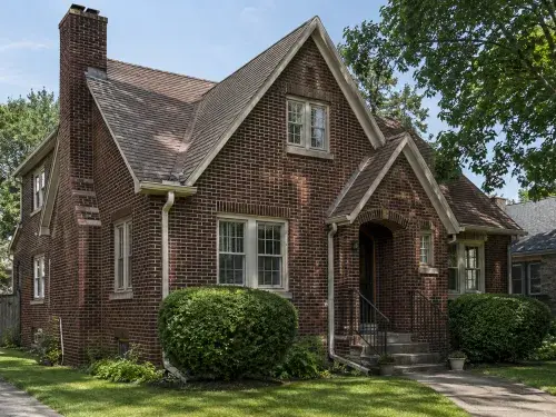 Authentic 1930s brick house exterior with steep gables, original windows, and front stoop.