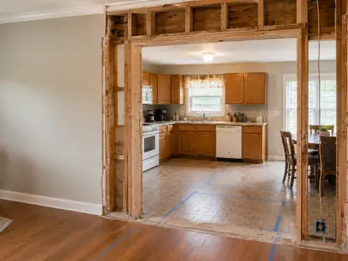 Opened wall above a ranch kitchen doorway showing exposed studs and inspection framing.