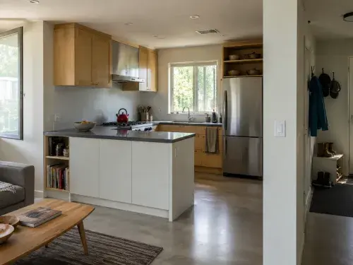 Modest sustainable home kitchen with open window, range hood, durable floor, and dry entry.