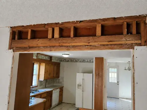 Opened wall above a ranch kitchen doorway showing exposed framing and drywall cuts.