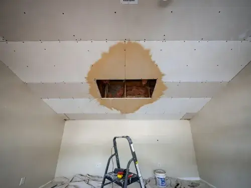 Wet ceiling drywall with a small cutout exposing the leak area above the damaged patch.