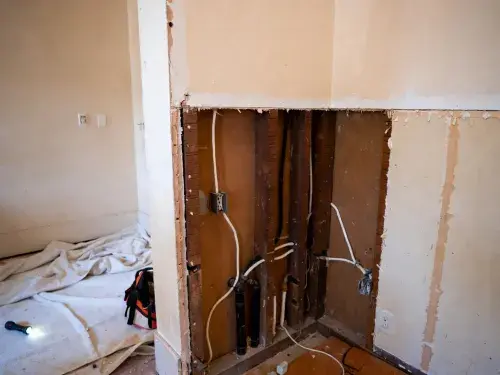 Opened wall in an old house showing wiring and plumbing during renovation.