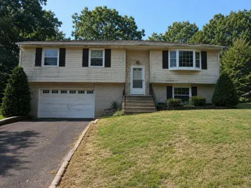 Dated raised ranch exterior with worn lawn, plain stairs, and weak front entry before remodeling.