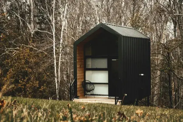 A sleek modern tiny house located on the edge of a forest.