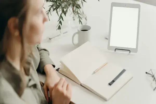 interior designer sitting beside a table with an iPad, paper, and pen, looking distant and confused as if struggling with too many ideas