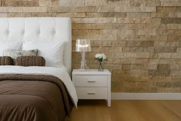 Modern bedroom interior featuring a natural stone accent wall, white headboard, and minimalist decor.