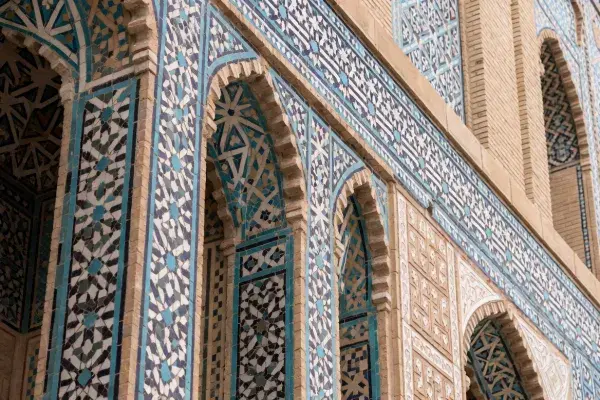 Arabic geometric tilework on arched facade with blue mosaic patterns and carved architectural detail.