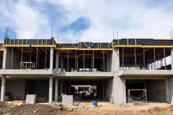 Partial concrete building structure under construction with scaffolding and construction materials, representing a CMAR project site.