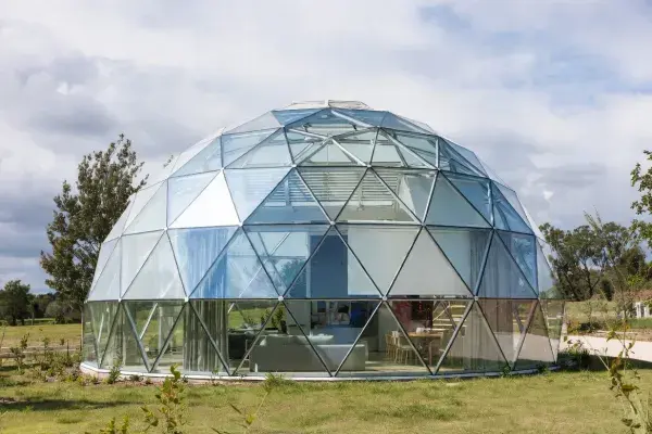 Glass dome house with visible glazing, curtains, and mixed transparent and opaque panels in a residential setting.