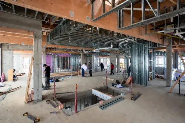 Ground-level framing and ductwork in a healthcare construction site with exposed studs and concrete columns.