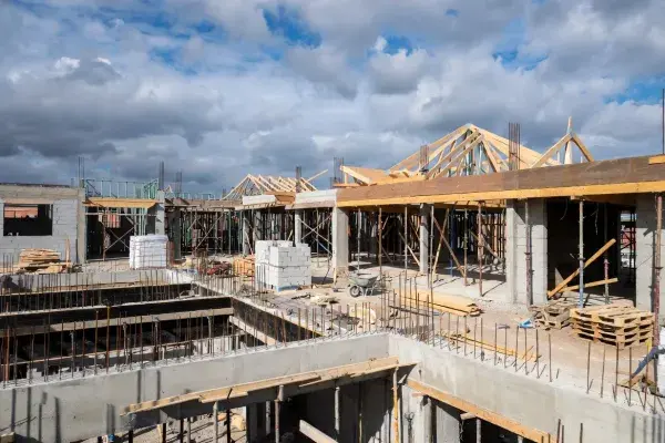 Concrete, masonry, and roof framing in progress on an active building site.