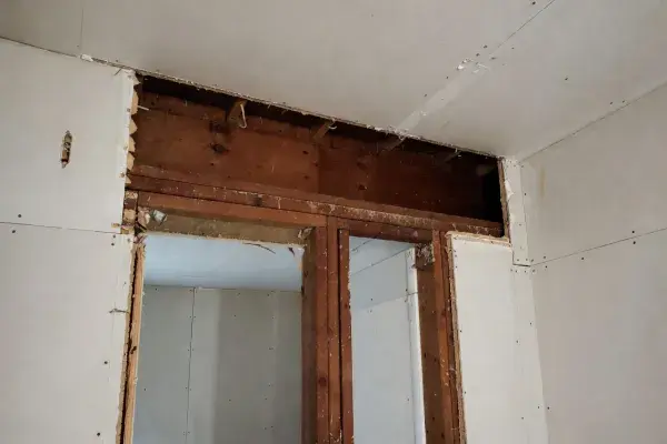 Older house wall opened above a doorway to inspect framing and header conditions.