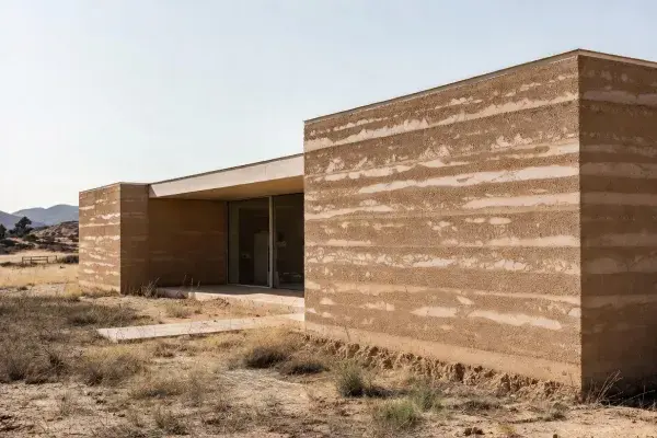 Modern rammed earth house with thick monolithic walls designed for sustainable living.