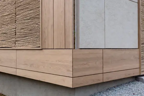 Modern facade with vertical timber cladding, light mineral framing, and deep window openings.