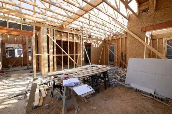 Residential construction site showing wooden framing, foundation, and structural layout.